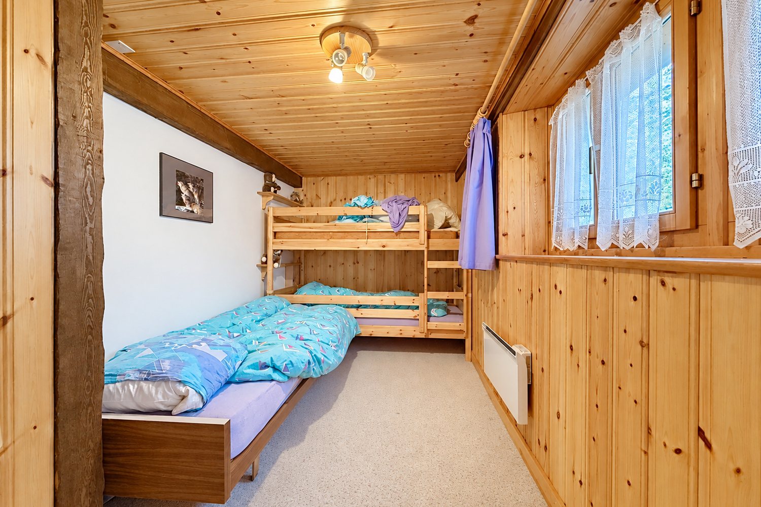 Seconde chambre de la maison : lits superposés et lit simple sous les lambris de sapin.