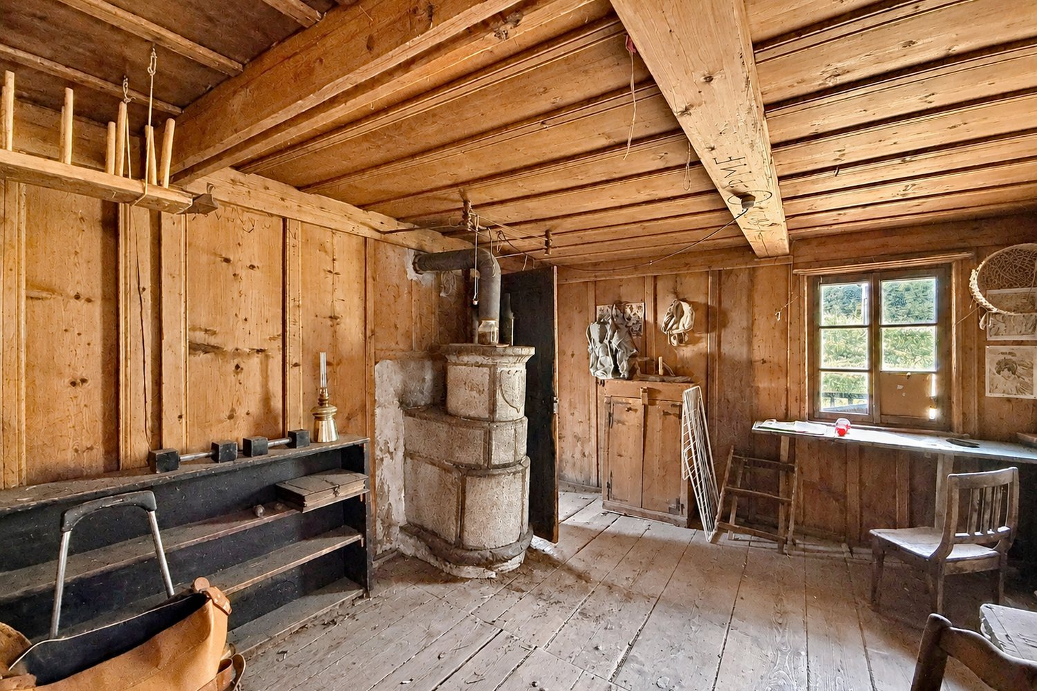 Pièce ancienne de la maison avec son fourneau en pierre ollaire, ses boiseries et son plancher peint.