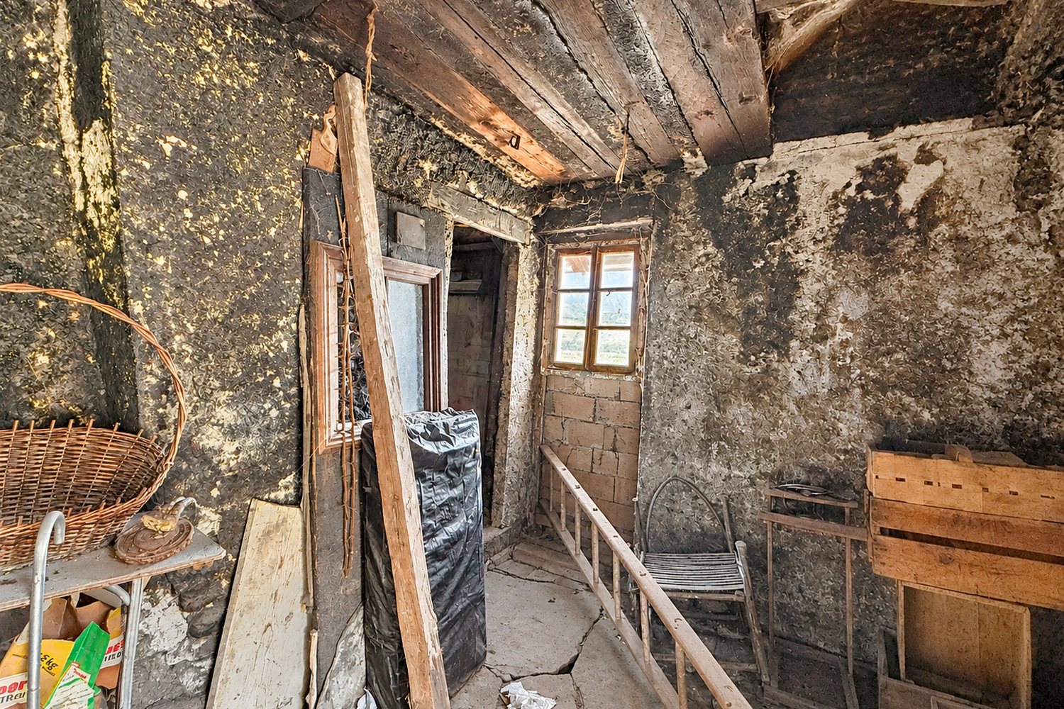 Le fumoir de la maison : murs et plafond noircis par des décennies de fumage, petite fenêtre sur le hameau.