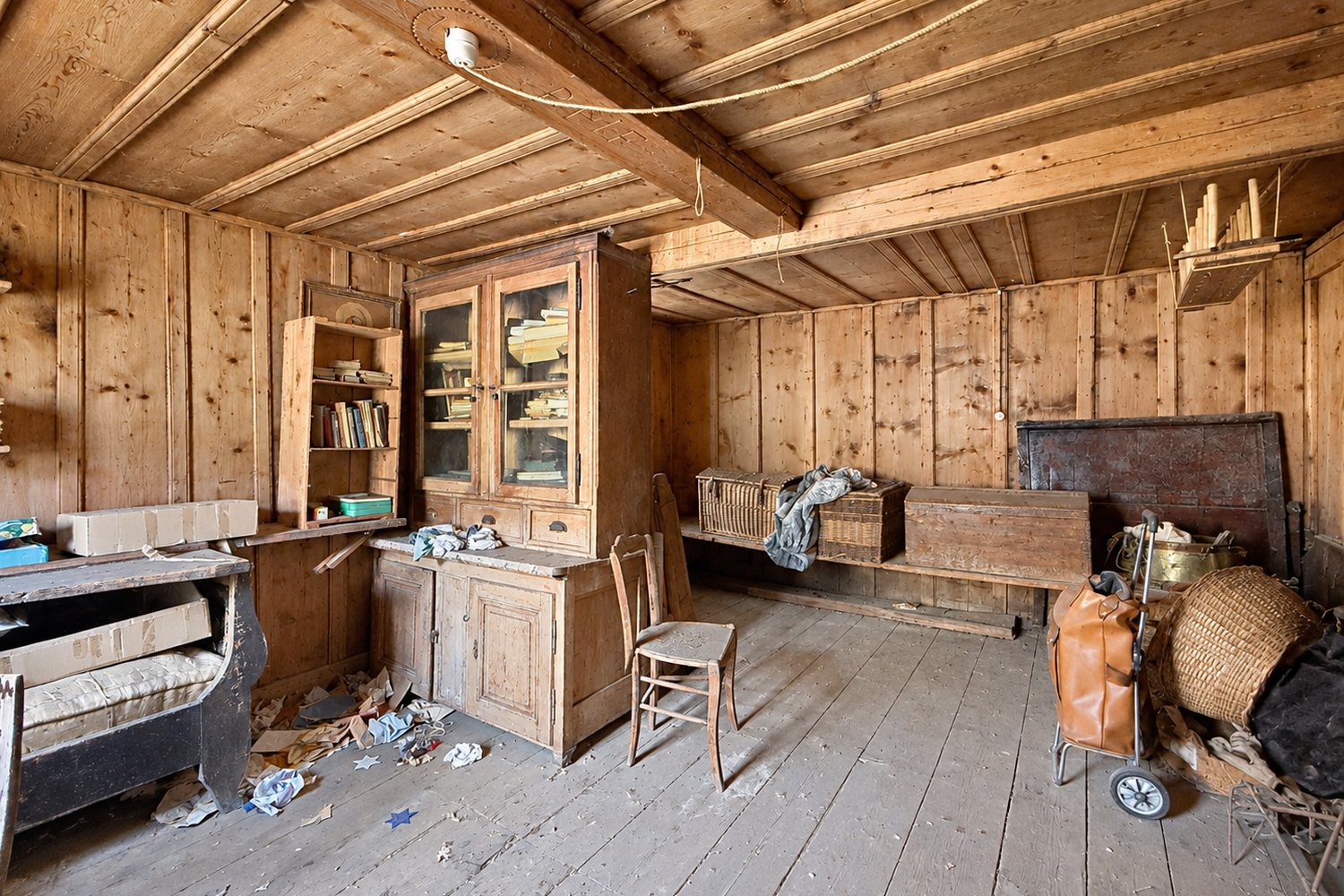 Chambre d'appoint de l'étage dans son état d'origine : lambris, vaisselier vitré et plancher gris.