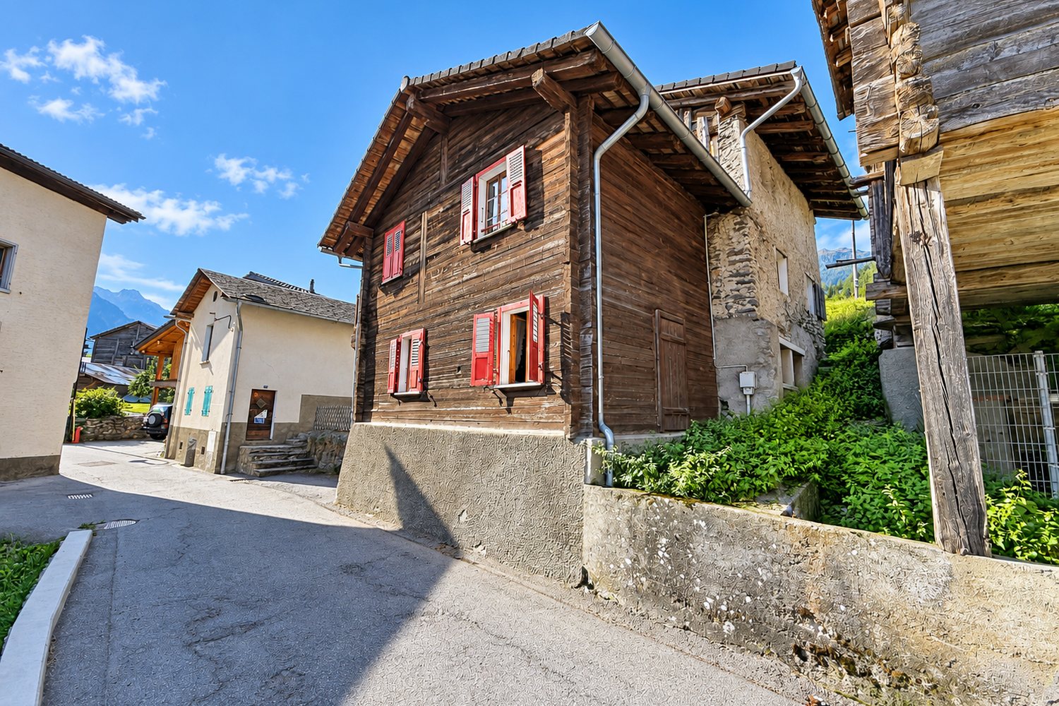 La ruelle du hameau du Sapey : le pignon de la maison en madriers entre les granges et les maisons voisines.